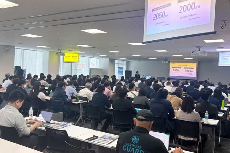【アフターレポート】満員御礼!「第2回 次世代TCGショップカンファレンス」 1 提案案: 秋葉原UDXで開催された、第2回次世代TCGショップカンファレンスの満員の会場全体の様子。前方スクリーンを見つめる多くの参加者の背中が写っている。